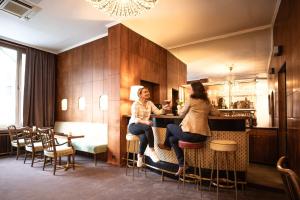 维也纳Select Hotel Prinz Eugen Wien的两名妇女在餐厅酒吧里坐