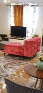 KoforiduaNana Adu Guest House的客厅配有红色沙发和电视