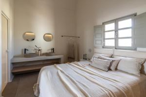 梅萨雷亚Frescoes Luxury Suites的白色卧室设有床铺和水槽