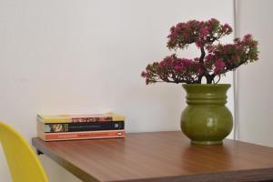 内罗毕Juliett Wonder Furnished Apartment的绿花瓶,桌子上放着鲜花,还有书