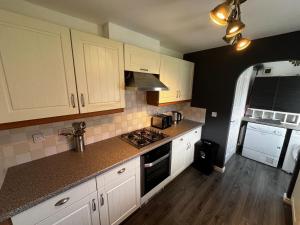 西部德比Modern 3 Bedroom House Close to Liverpool Centre的厨房配有白色橱柜和炉灶烤箱。