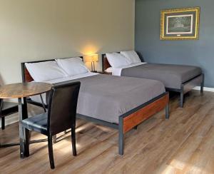 霍玛Red Carpet Inn - Houma的配有一张桌子和一把椅子的客房内的两张床