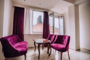 奥赫里德Villa Afrodita City Center的一间设有两张紫色椅子、一张桌子和一个窗户的房间