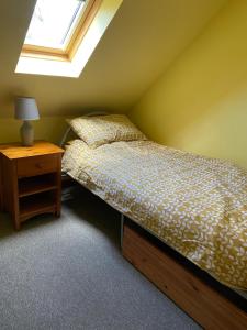威廉堡斯布伦维尔度假小屋的一间卧室配有一张床和一个带窗户的床头柜