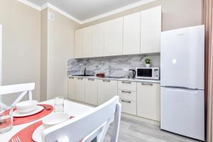 阿斯塔纳Grand Turan Business Apartments的白色的厨房配有桌子和白色冰箱