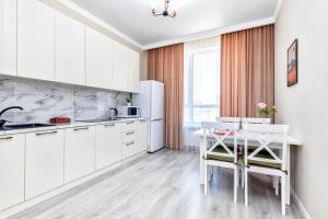 阿斯塔纳Grand Turan Business Apartments的厨房配有白色橱柜和白色桌子
