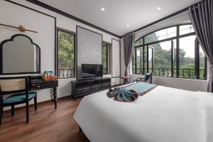 宁平Indochine Boutique Hotel Ninh Bình的一间卧室配有一张床和一张书桌及电视