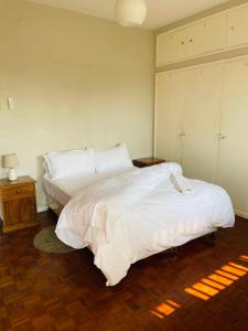 马普托Januario Maputo的一间卧室配有一张带白色床单的大床