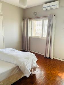 马普托Januario Maputo的卧室配有白色的床和窗户。