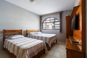 圣若昂-德雷Aconchego São Francisco, Casa 100m Igreja São Francisco, Pet friendy的一间卧室设有两张床、一台电视和一扇窗户。