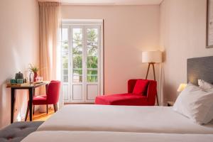 里斯本Bica FLH Suites的酒店客房,配有一张床和两张红色椅子