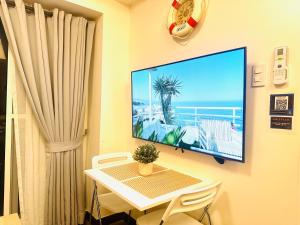 马尼拉CELANDINE Residence by DMCI的一间设有桌子的房间和墙上的电视