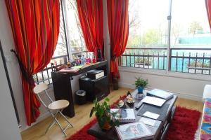 蒙鲁日La bambouseraie的一间设有红色窗帘的客房,并在窗户前设有一张书桌