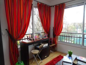 蒙鲁日La bambouseraie的一间设有红色窗帘的客房,并在窗户前设有一张书桌