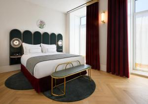 里斯本Montebelo Vista Alegre Lisboa Chiado Hotel的一间卧室配有一张大床和一把椅子