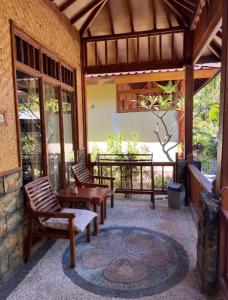 吉利阿尔Sunny Rose Bungalows Gili Air的庭院配有两把椅子、一张桌子和一张桌子