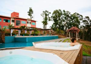 卡皮托利乌Hotel Chalé Capitólio的游泳池旁的热水浴池中的女性
