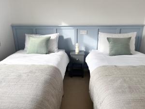 基督城Peaceful Riverside Lodge的两张睡床彼此相邻,位于一个房间里