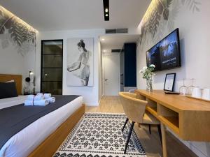 地拉那Retreat Apartments的一间卧室配有一张床、一张书桌和一台电视
