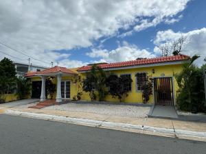 Catano3BR, 1BA Spacious Property in Cataño, Near Bacardí的街上有红色屋顶的黄色房子