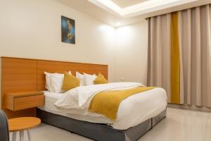 利雅德Al Nakheel Park Serviced Apartment的一间卧室配有一张带白色和黄色枕头的大床