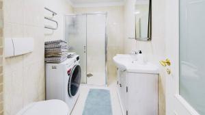 塔林TallinnHousing Old Town Homes - 3 BDR Apartment in Rüütli的白色的浴室设有洗衣机和水槽。
