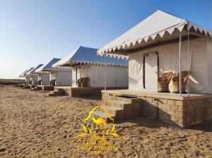 山姆Jaisalmer Unique Desert Camp的沙滩上的一排白色帐篷