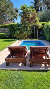 卢汉德库约Chacras de Coria Relax的两个木凳坐在游泳池旁