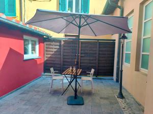 卢卡Cortile in centro - Charm Suite Heart of Lucca的露台的遮阳伞下的桌椅