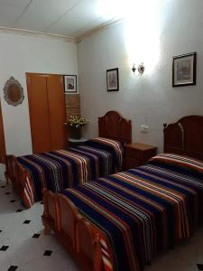 Catí卡萨安琪利塔旅馆的配有带条纹床单的酒店客房内的两张床