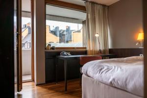 斯德哥尔摩斯堪迪克安格莱斯酒店的配有一张床、一张书桌和一扇窗户的酒店客房