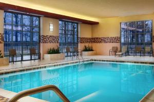 康科德Embassy Suites by Hilton Charlotte Concord Golf Resort & Spa的游泳池位于酒店客房内,配有桌椅