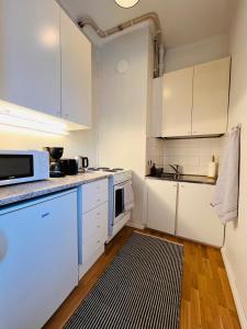 赫尔辛基Your Chic Vibrant Airbnb的厨房配有白色橱柜和黑白地毯。