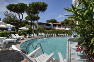 利尼亚诺萨比亚多罗阿里赛酒店的一个带白色椅子和一束家具的游泳池