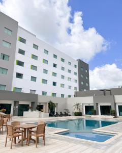 比亚埃尔莫萨Courtyard by Marriott Villahermosa Tabasco的一座带游泳池和椅子的酒店和一座建筑