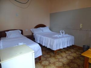 廷戈玛丽亚Hostal Ucayali的一间设有两张带白色床单的床的房间
