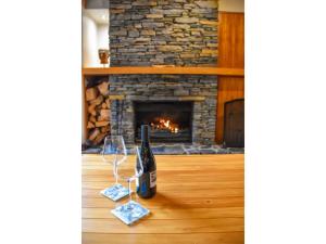 图朗伊白桦林河畔酒店的壁炉前的桌子上放着一瓶葡萄酒和玻璃杯