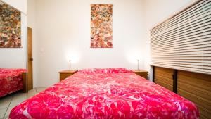 阿鲁坦加卡帕卡帕度假屋的一间卧室设有一张红色大床和两个窗户。