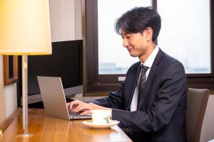 泉佐野王子空港城市酒店的坐在一张桌子上,手提电脑的男人