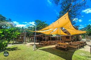 Glamper Grove- Real, Quezon的大型黄色帐篷,配有木桌和长凳