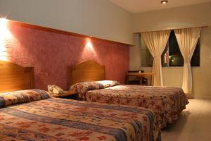 CuauhtémocTarahumara Inn的红色墙壁的酒店客房内的两张床