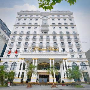 河江Phoenix Hotel Hà Giang的一座白色的建筑,前面有棕榈树