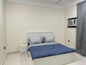 麦地那Almansour Laxury Apartement的白色卧室,配有一张带蓝色棉被的床