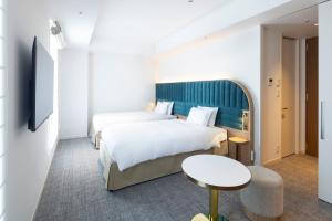 横滨Hotel Comento Yokohama Kannai的酒店客房设有两张床和一张桌子。