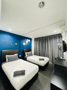 Wakaf BaharuHalo Rooms Hotel的酒店客房设有两张床和蓝色的墙壁。