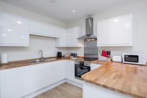 梅登黑德Luxury Apartments 2 Bedrooms Central Maidenhead的厨房配有白色橱柜和木制台面