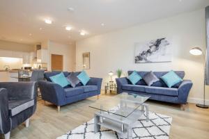 梅登黑德Luxury Apartments 2 Bedrooms Central Maidenhead的客厅配有2张蓝色的沙发和1张桌子