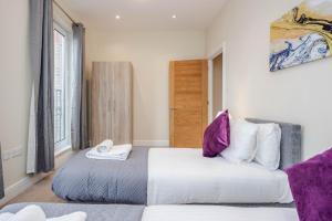 梅登黑德Luxury Apartments 2 Bedrooms Central Maidenhead的一间卧室配有两张带紫色枕头的床