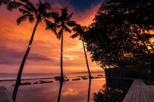 甘地达萨Villa Manis Beachfront Candidasa的棕榈树和游泳池的日落