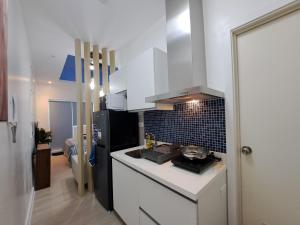圣费尔南多Hailey's Crib @ Azure North的厨房配有白色橱柜和黑色冰箱。